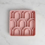 Pink silicone ice cube tray with arch-shaped molds