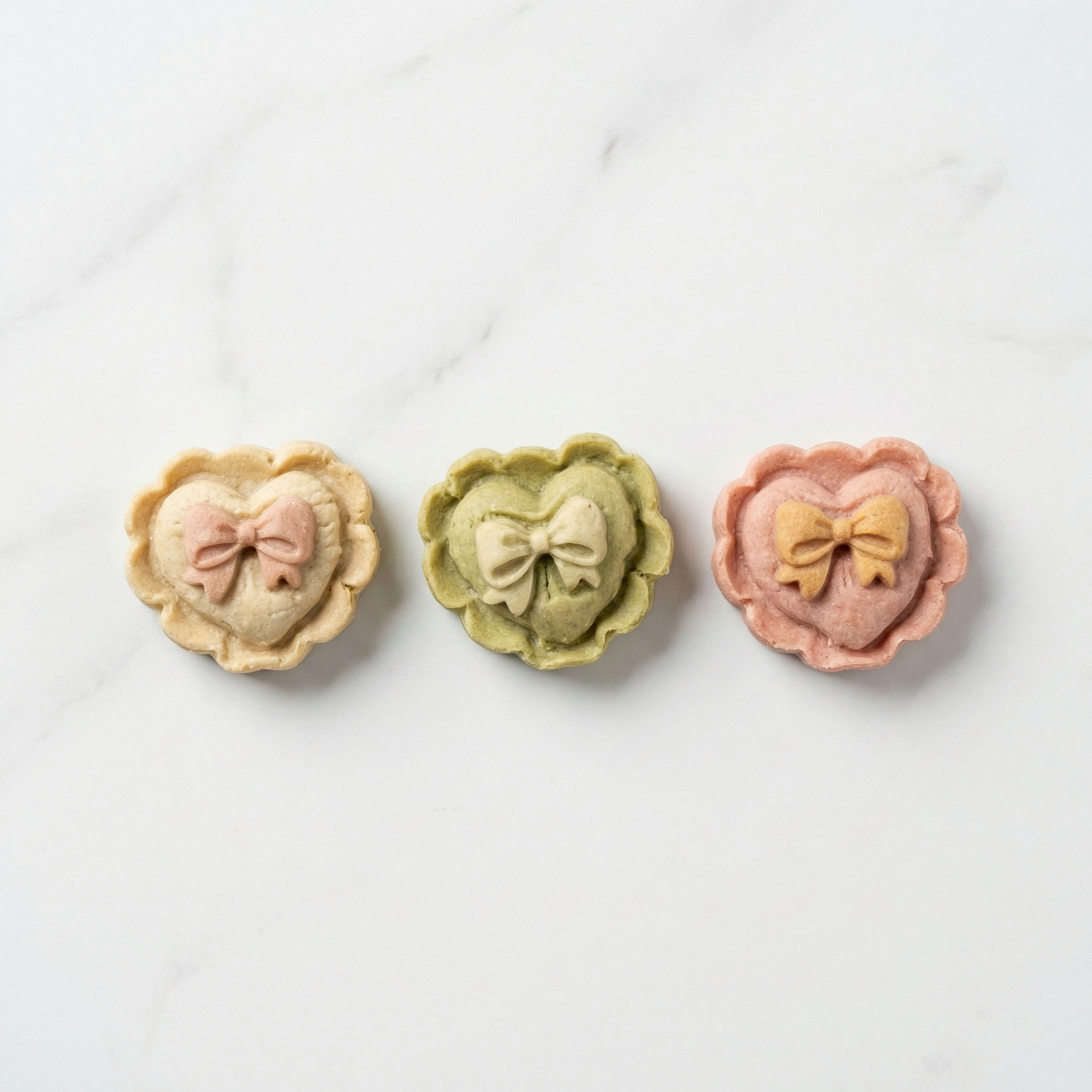 Three heart-shaped pastries with bow decorations on a white background