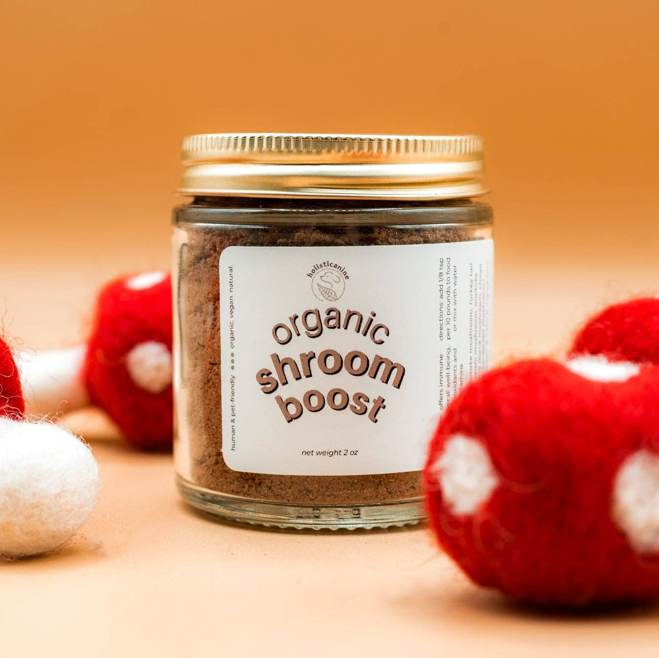 Jar of 'organic shroom boost' with red and white mushroom decorations on a wooden surface.