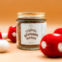 Jar of 'organic shroom boost' with red and white mushroom decorations on a wooden surface.
