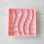 Pink silicone mold with wavy patterns on a white background