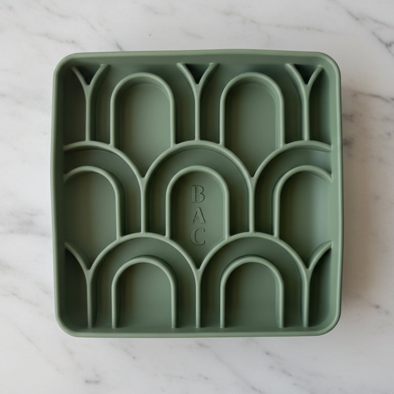 Green silicone tray with arch-shaped compartments on a white background