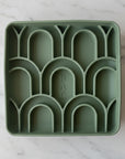 Green silicone tray with arch-shaped compartments on a white background